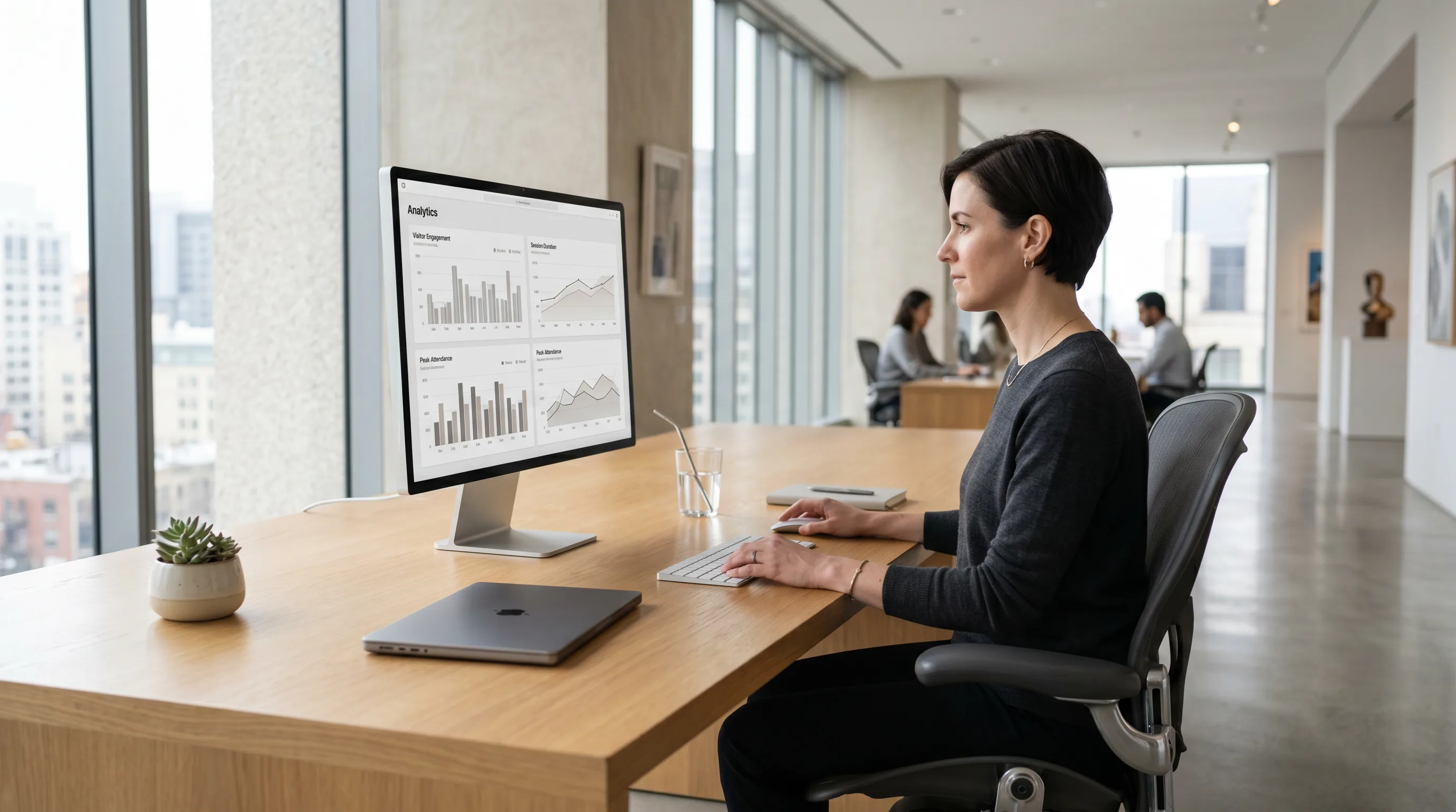 Museum professional reviewing visitor analytics on a sleek monitor in a bright modern office.